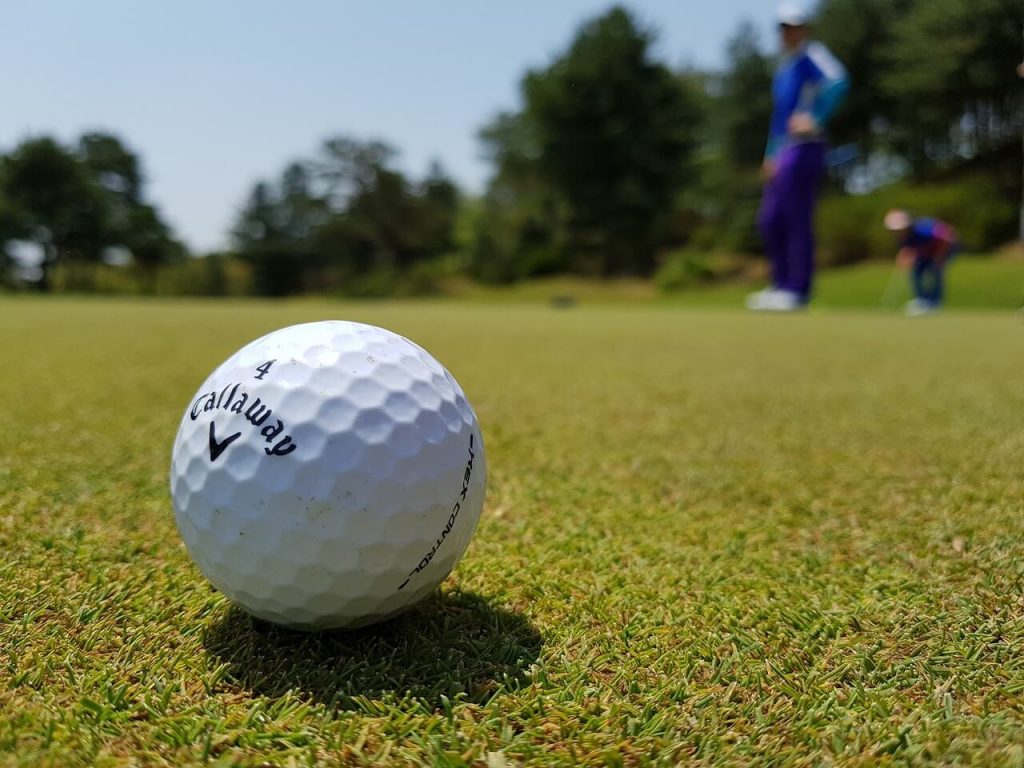 Vibrant Callaway golf ball lying gracefully on the lush green grass of the fairway.