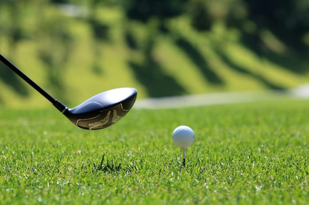 Golfer in mid-swing, confidently striking the golf ball with a powerful club.