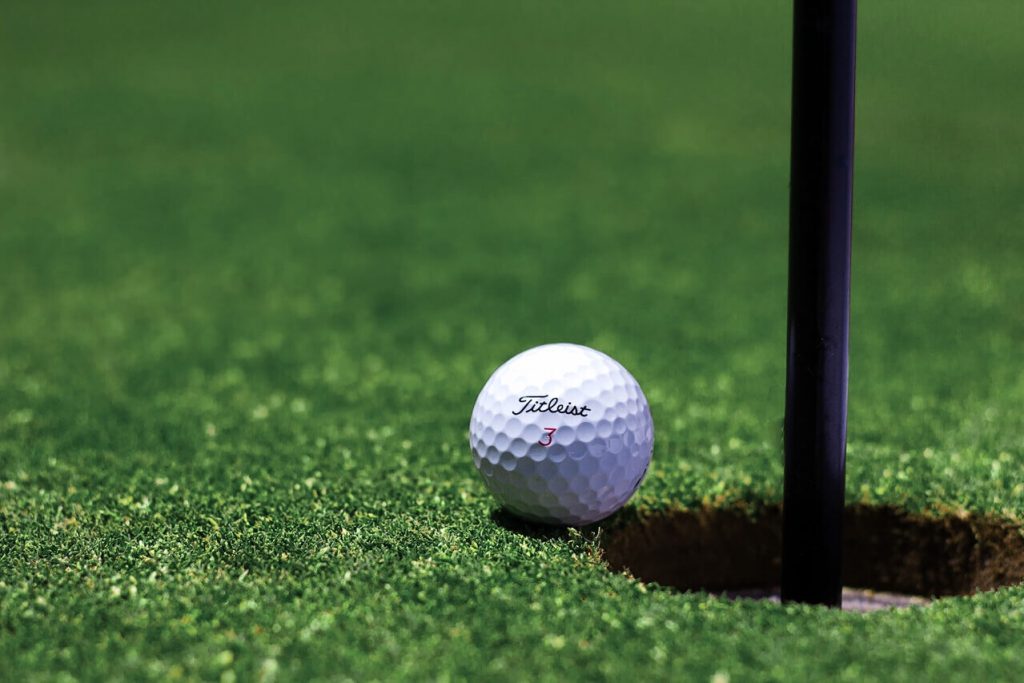 Close-up of a Titleist golf ball inches away from the hole on a well-maintained green.